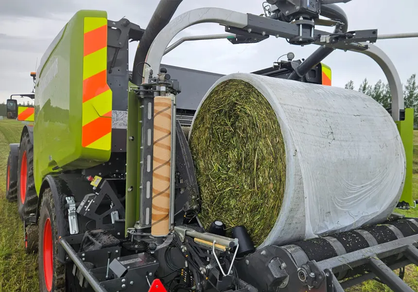 Baler wrapping a round silage bale with net replacement film during field trials